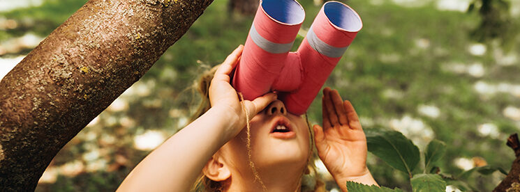 Closeup portrait of little girl looking through a binoculars sea